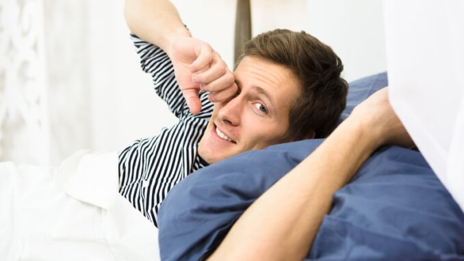 Happy man sleeping in bed alone.