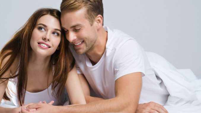 Portrait of young attractive happy couple on the bed at bedroom.