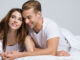 Portrait of young attractive happy couple on the bed at bedroom.