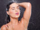 young woman in shower over black background
