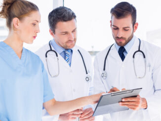 Two male doctors and female surgeon reading medical reports at the hospital