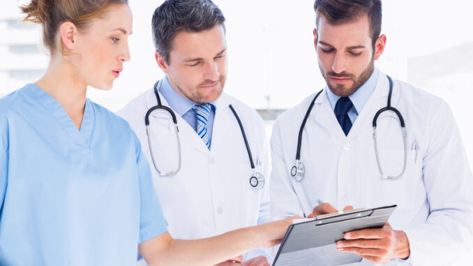 Two male doctors and female surgeon reading medical reports at the hospital