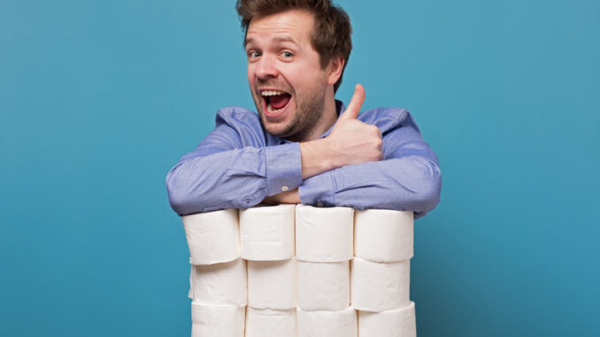 Excited happy caucasian man holding a pile of toilet paper showing thumb up isolated on blue background.