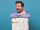 Excited happy caucasian man holding a pile of toilet paper showing thumb up isolated on blue background.