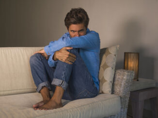 Lifestyle portrait of young attractive and handsome sad latin man sitting tired