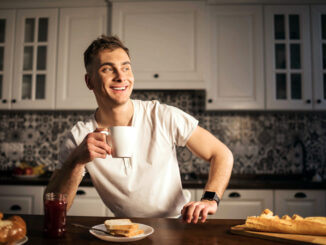 Handsome man drinking coffee at home in the kitchen