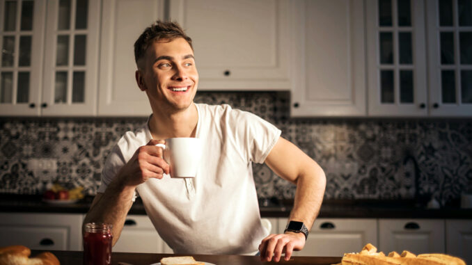 Handsome man drinking coffee at home in the kitchen