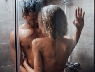 nude heterosexual couple looking at each other, embracing and taking shower together