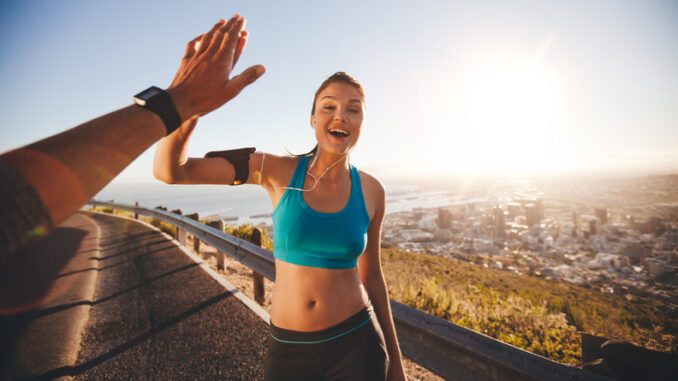 Fit young women high fiving her boyfriend after a run.