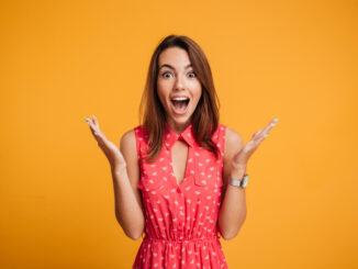 Close-up portrait of young pretty surprised woman with opened mouth standing with open palms,