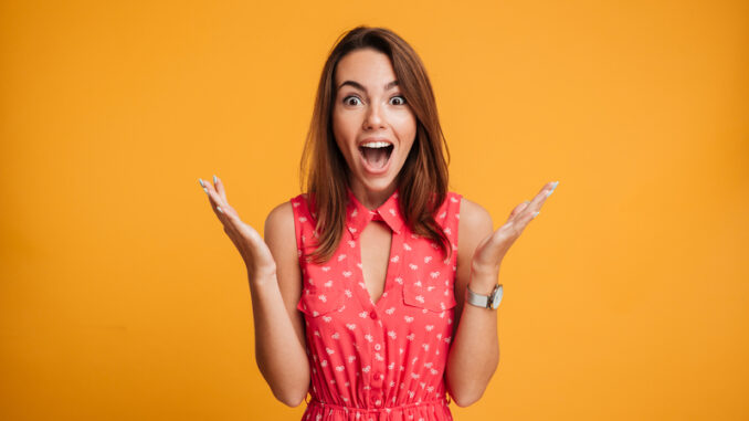 Close-up portrait of young pretty surprised woman with opened mouth standing with open palms,