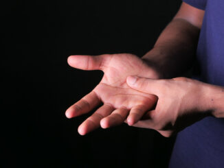 Man with hand pain isolated in black