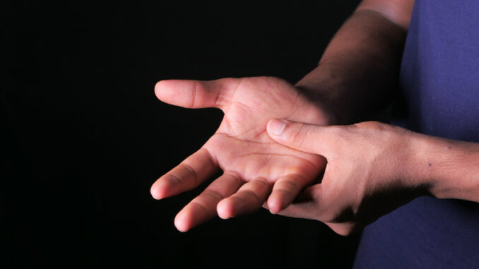 Man with hand pain isolated in black