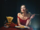 Young woman eating tasty pasta on black