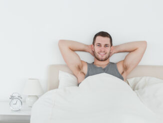 Happy man waking up in his bedroom