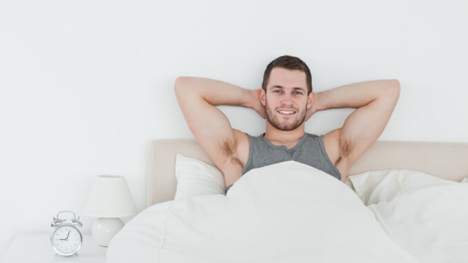 Happy man waking up in his bedroom