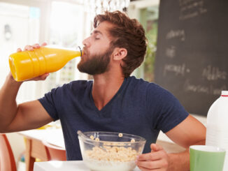 Young Man Eating Breakfast And Drinking Orange Juice