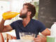 Young Man Eating Breakfast And Drinking Orange Juice