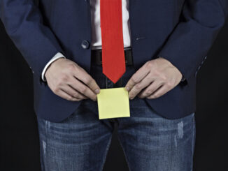 Man in suit, businessman holding sticker in his groin area