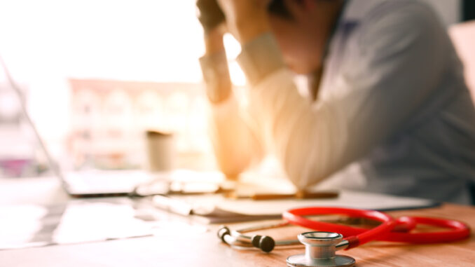 Young man doctor being exhausted in the office room