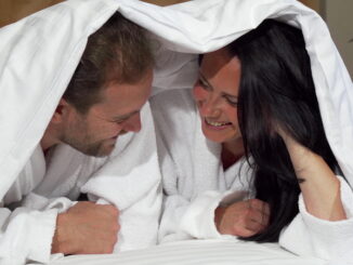 Happy mature couple laughing joyfully, lying in bed together.