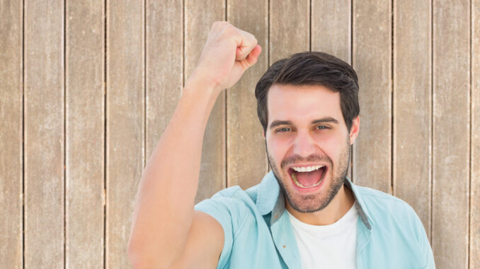 Happy casual man cheering at camera against wooden planks