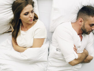 Top view of young upset couple lying in bed have problems after quarrel and angry to each other at home