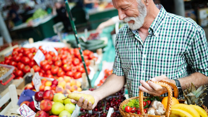 Handsome senior man shopping for fresh vegetable and fruit in a market