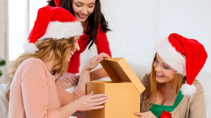 three smiling women in santa helper hats with many gift boxes