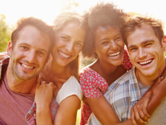 Two happy couples embracing and smiling to camera outdoors