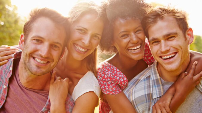 Two happy couples embracing and smiling to camera outdoors