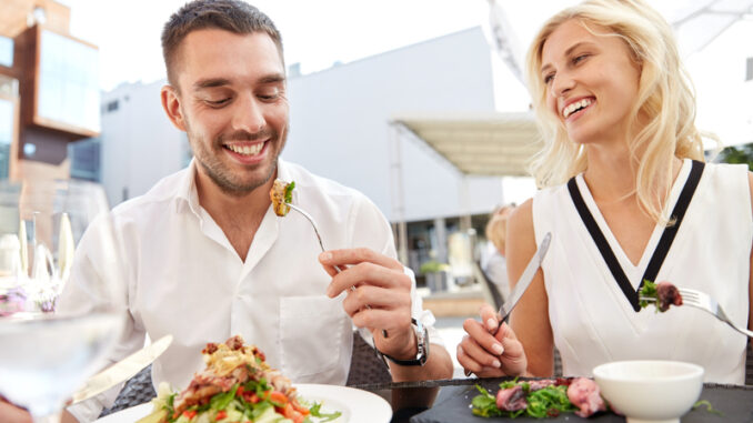 happy couple eating salad for dinner at cafe or restaurant terrace
