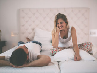 Happy couple in pajamas having conversation in bed