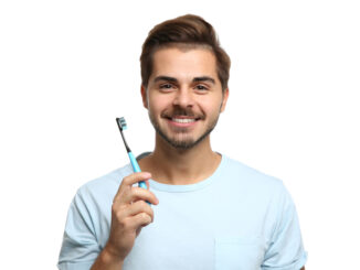 Portrait of young man with toothbrush on white background