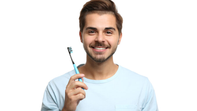 Portrait of young man with toothbrush on white background