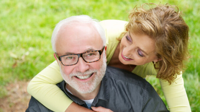 a happy older men with beautiful women smiling outdoors